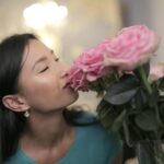 woman smelling perfume bottle in forest