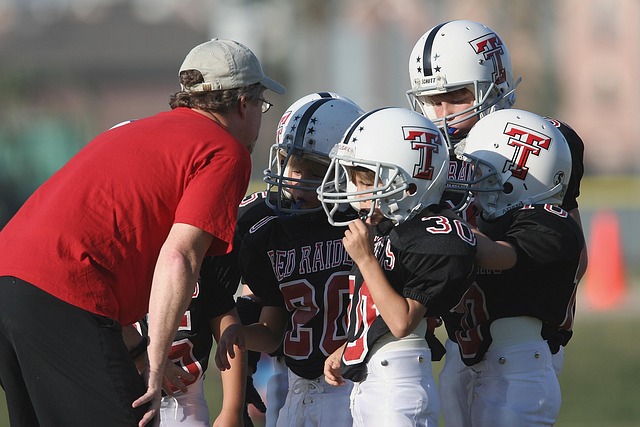 Coach speaking with a young athlete on the sidelines, gesturing calmly and constructively